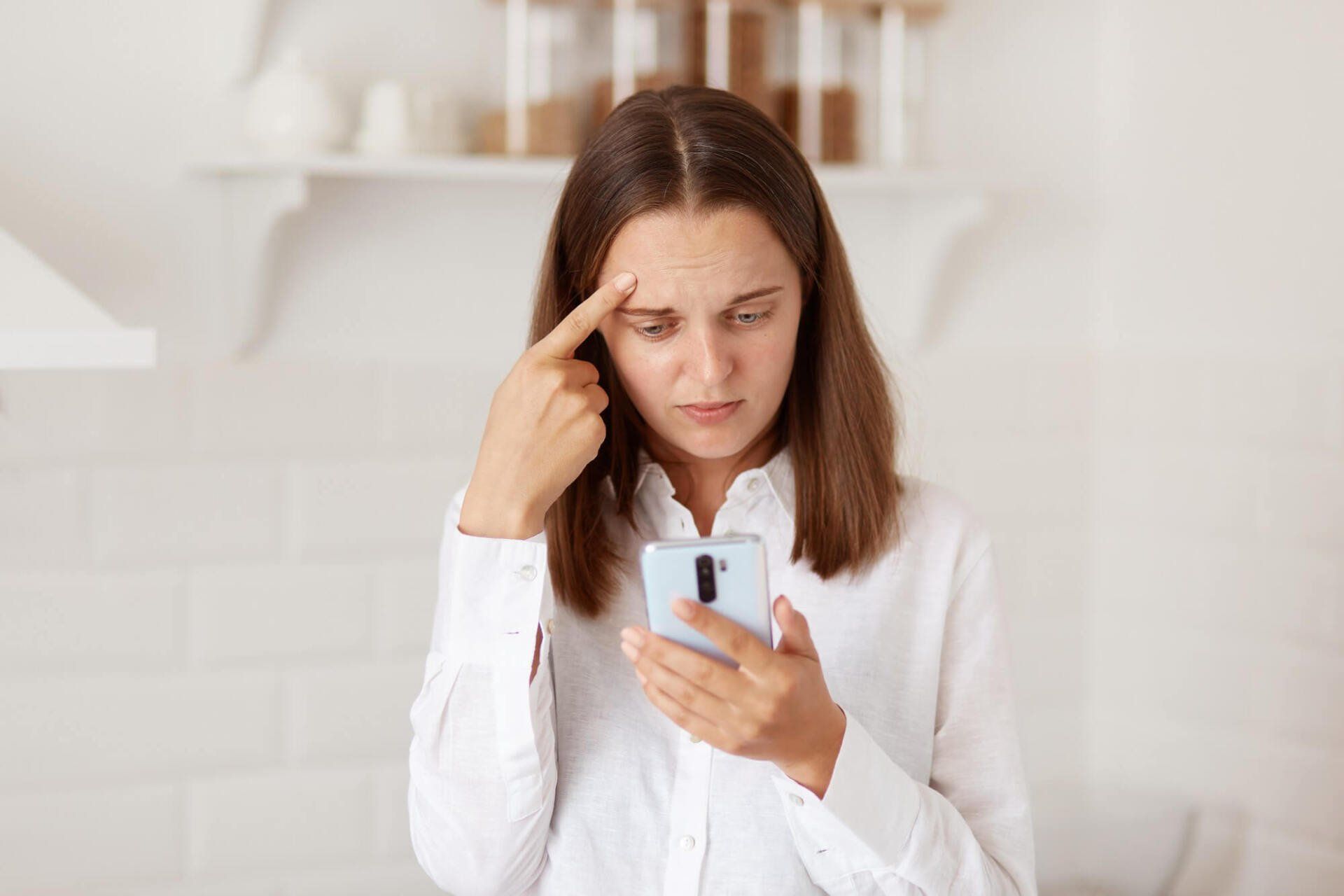 confused-puzzled-dark-haired-woman-standing-cell-phone-hands-checking-social-networks