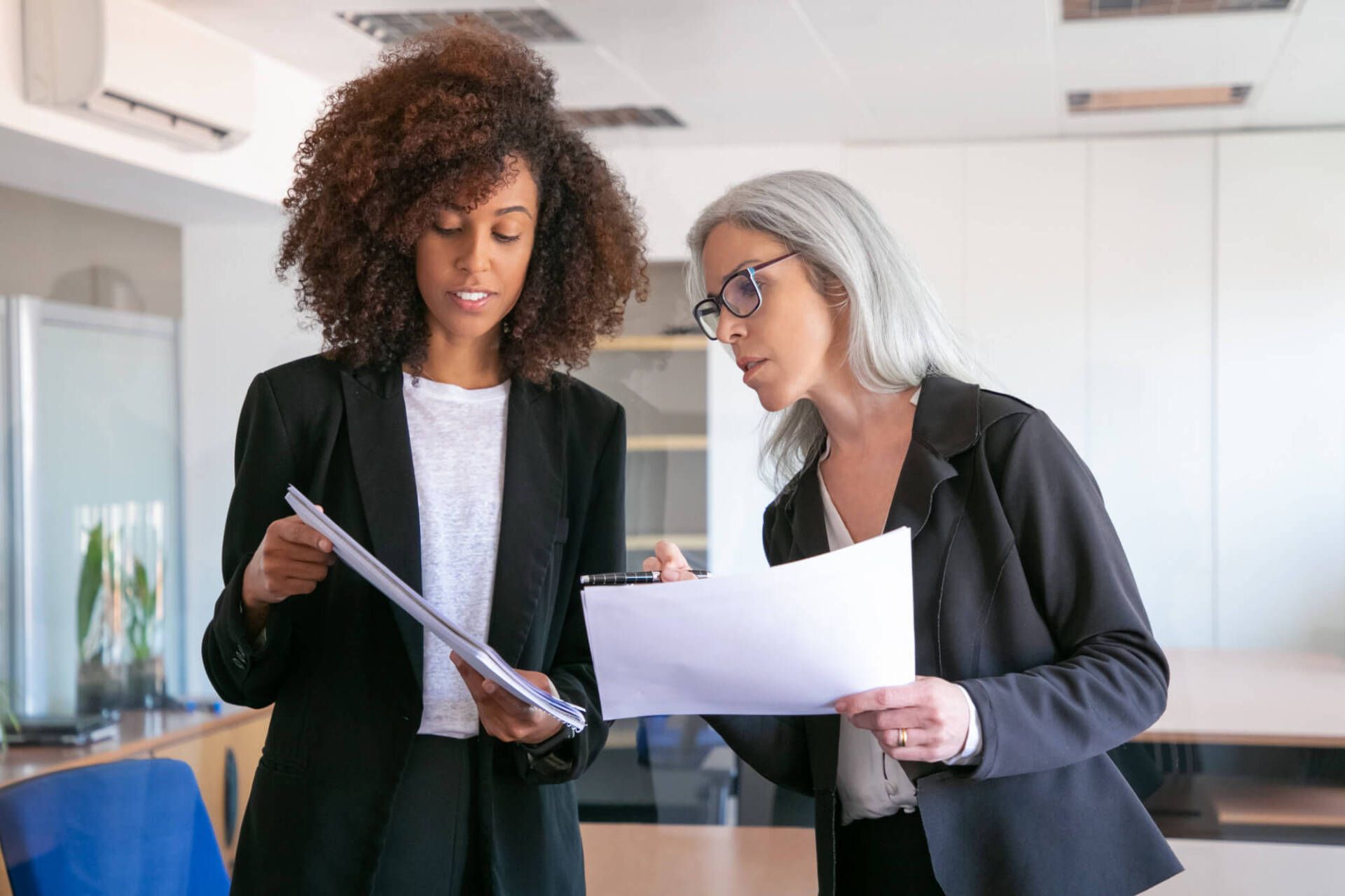 content-young-manager-showing-document-adult-colleague-two-pretty-content-female-colleagues