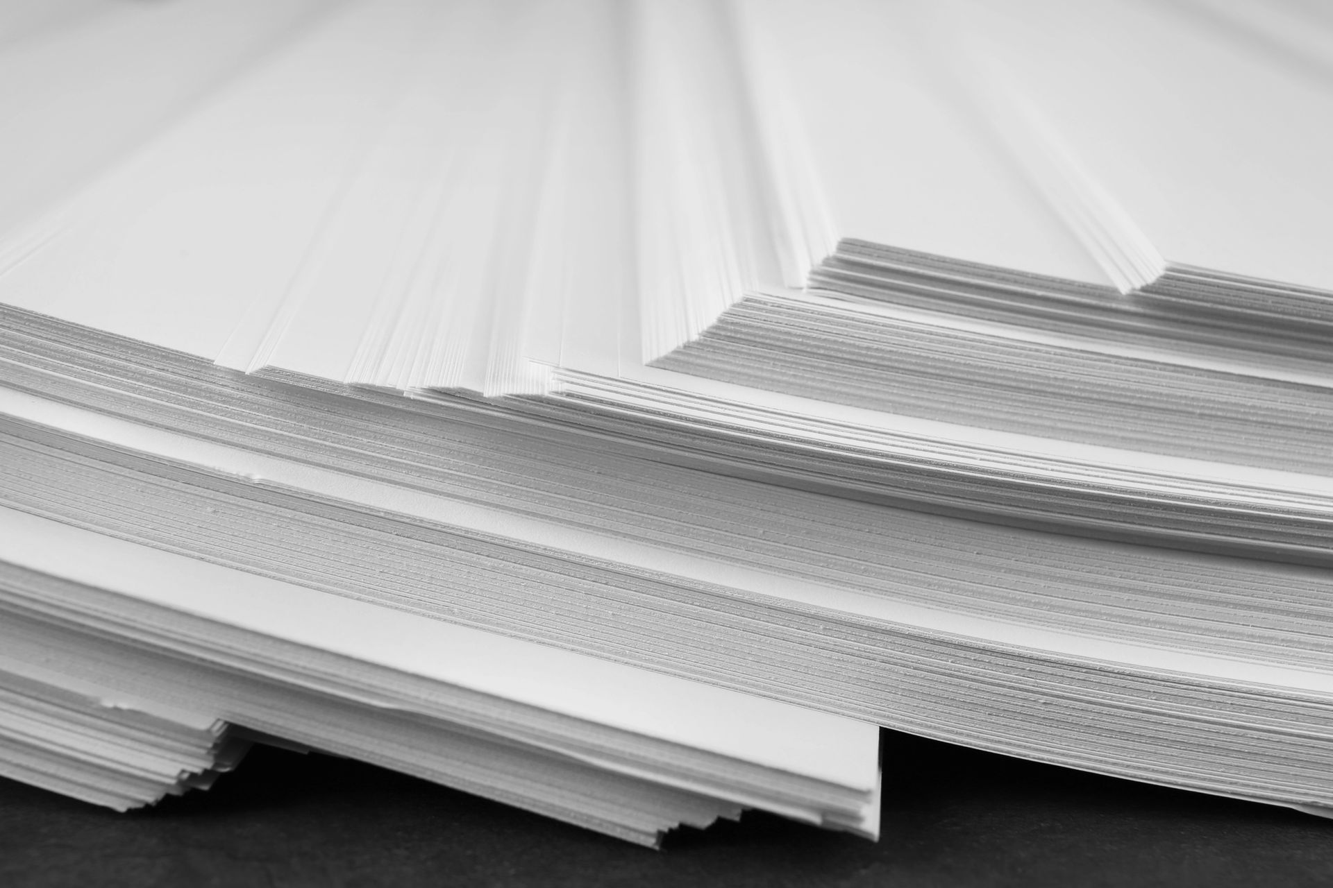 Un primer plano de una pila de papel blanco sobre una mesa.