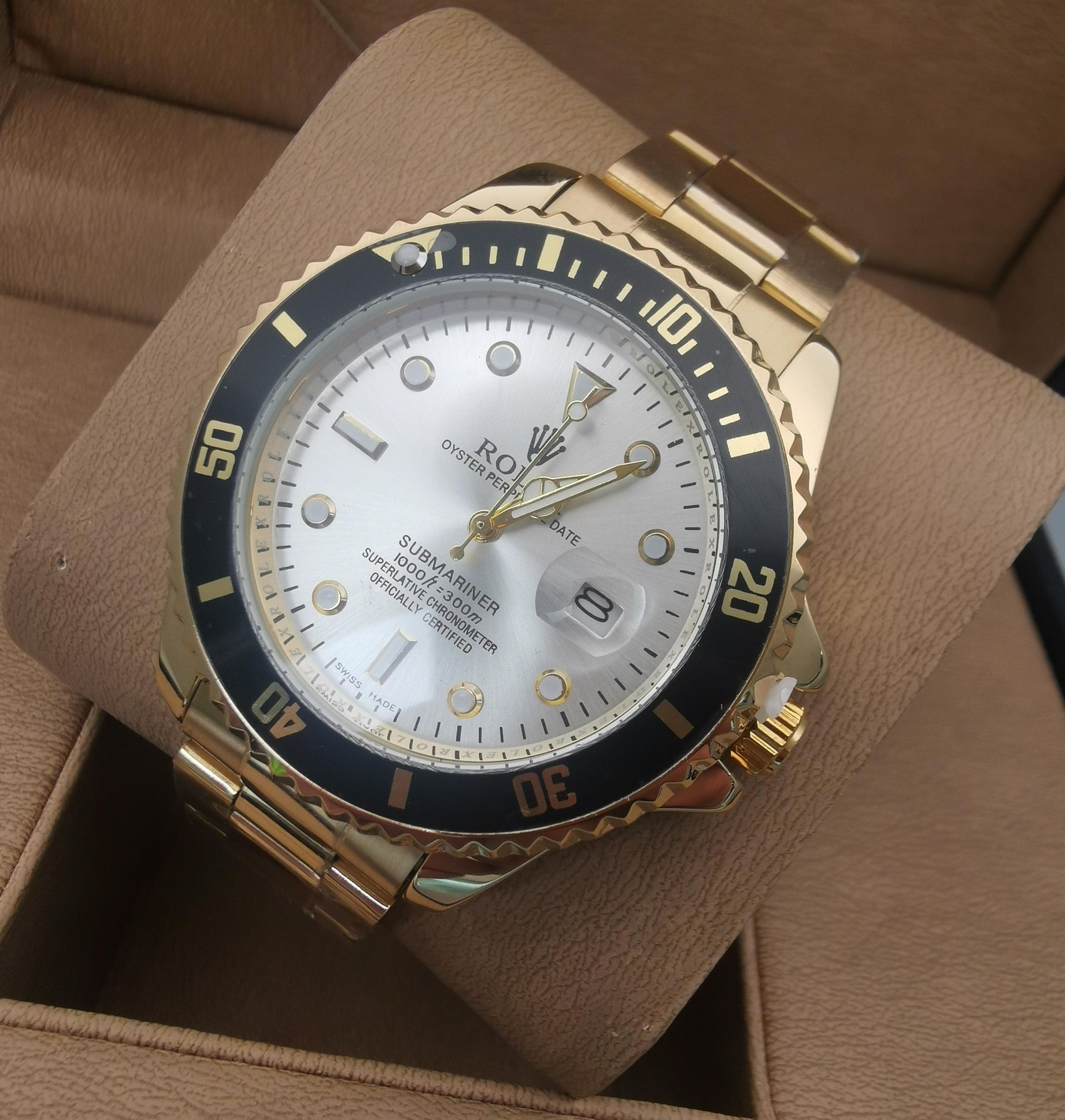 Reloj Rolex Submariner dorado con esfera y bisel azules, apoyado sobre una superficie color canela.