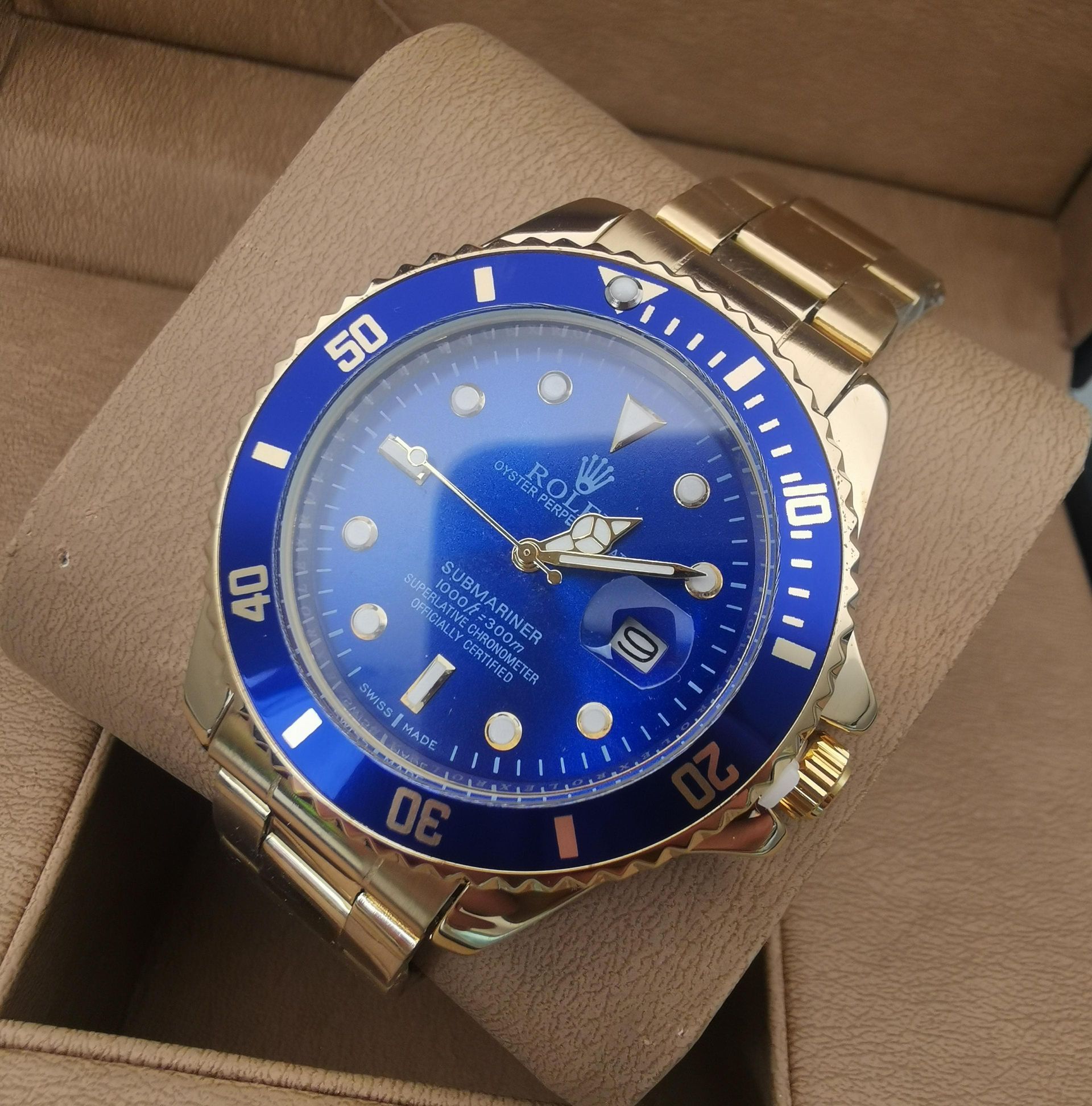 Reloj Rolex Submariner dorado con esfera y bisel azules, apoyado sobre una superficie color canela.