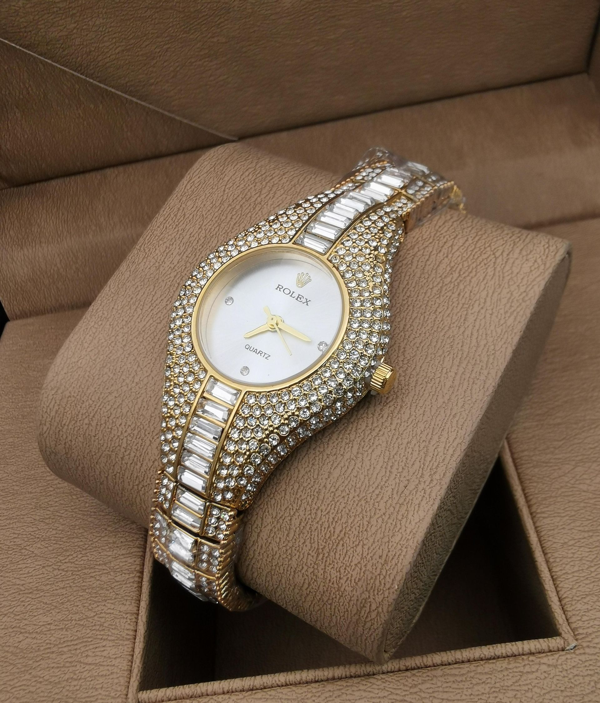 Reloj de pulsera con incrustaciones de oro y joyas sobre una almohada de reloj marrón