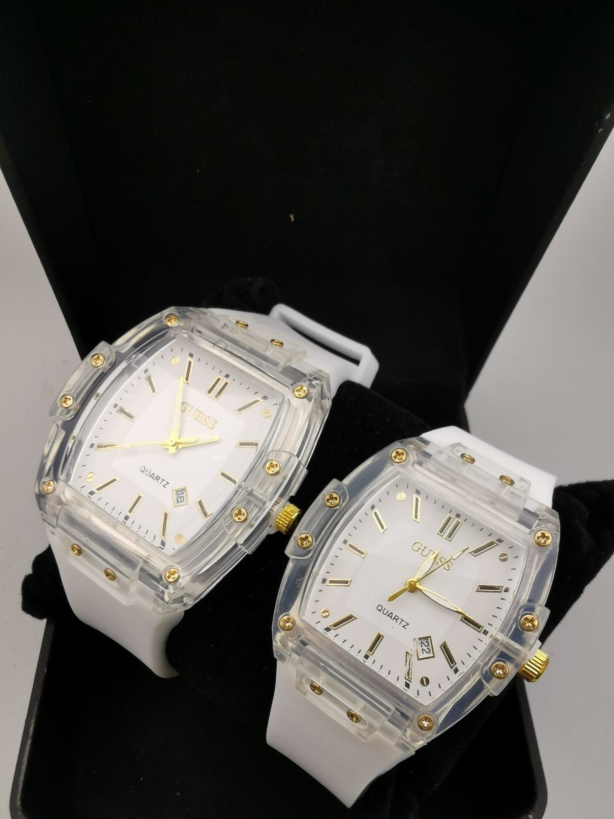 Dos relojes de cuarzo blanco y dorado en una caja negra.