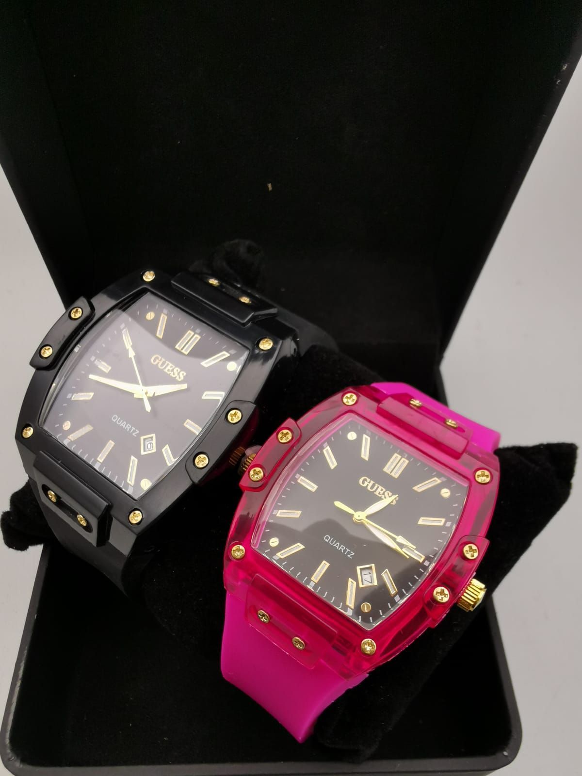 Dos relojes de cuarzo blanco y dorado en una caja negra.