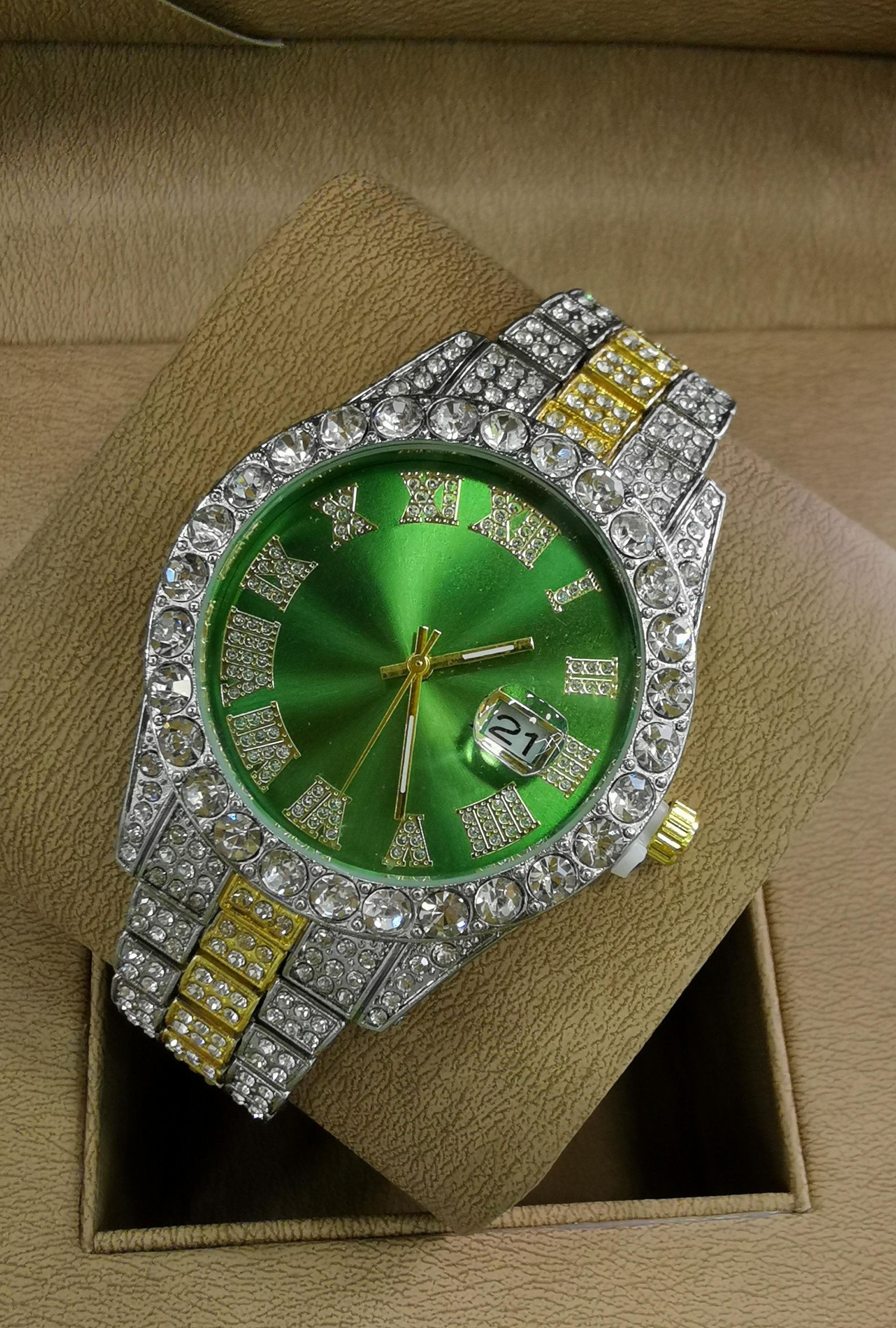 Reloj de pulsera con incrustaciones de diamantes y esfera roja, que reposa sobre un cojín beige en un joyero.