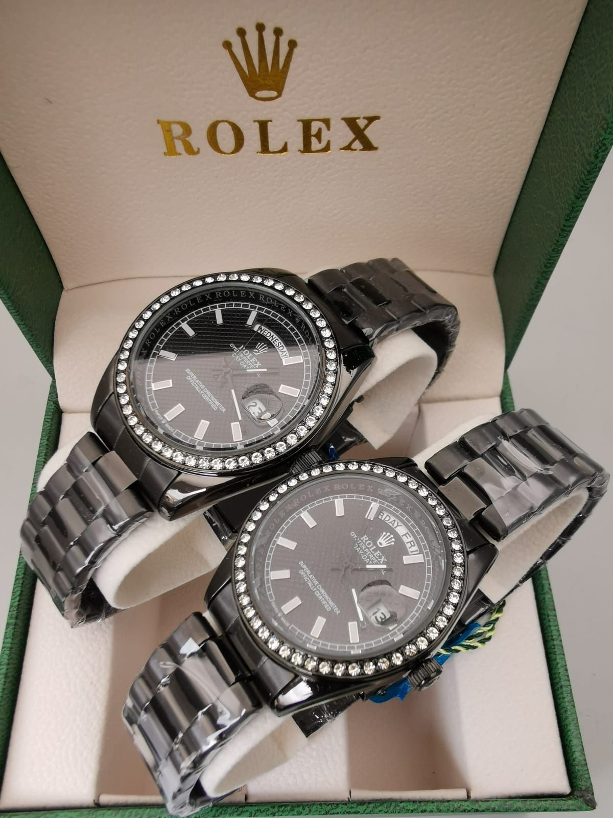 Dos relojes Rolex de oro con biseles de diamantes en una caja verde.