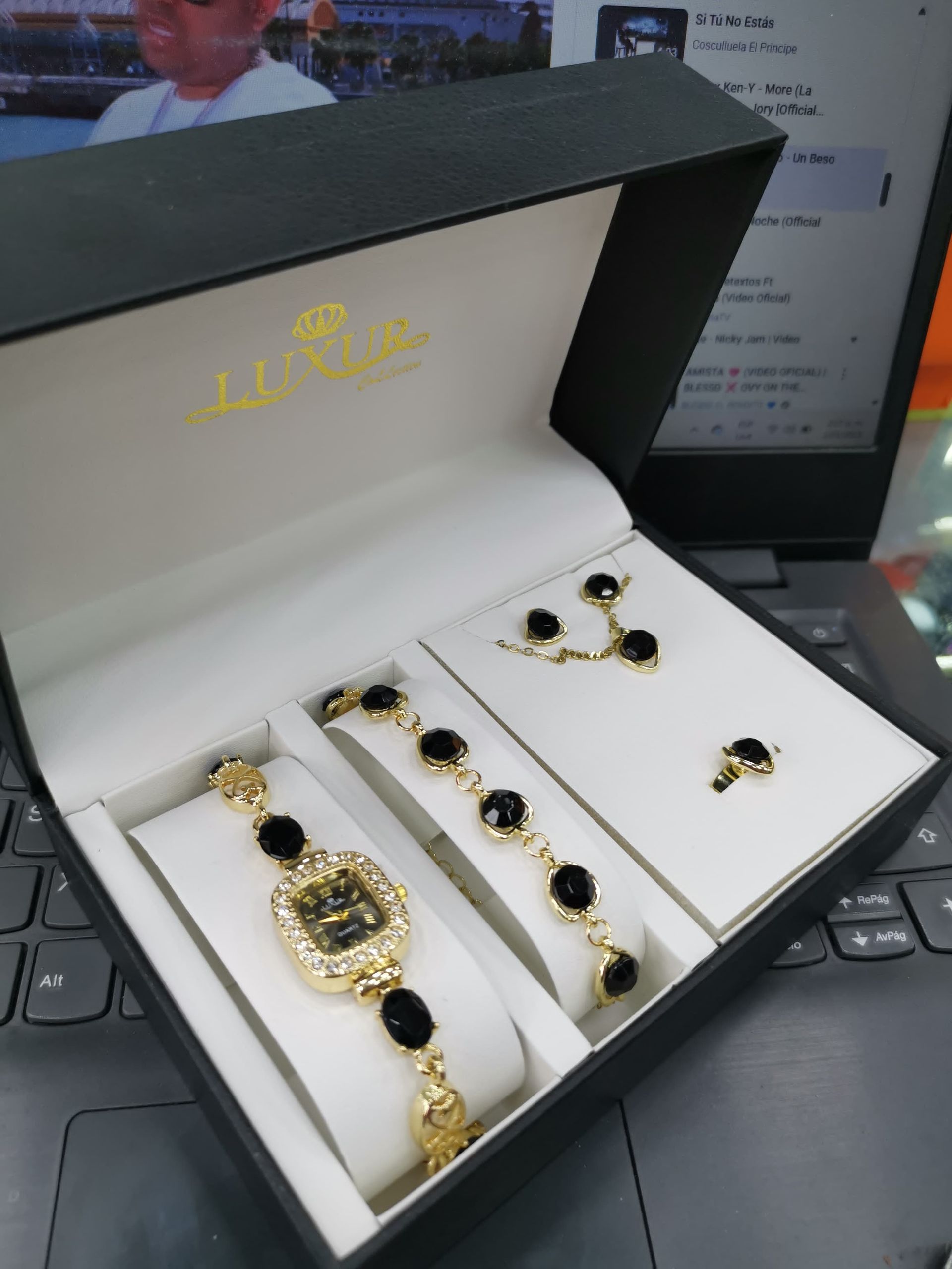 Conjunto de reloj, pulsera, pendientes y anillo en color negro y dorado en caja negra.