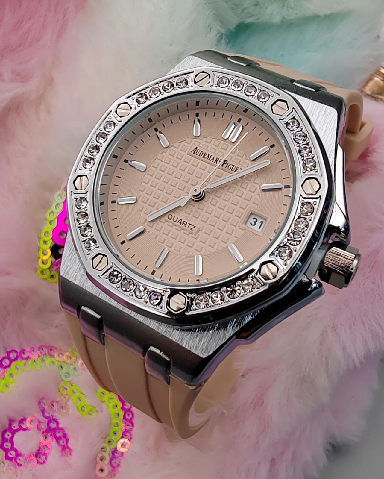 Reloj de oro rosa con esfera negra, bisel de diamantes y correa negra, que reposa sobre un material suave y pastel.