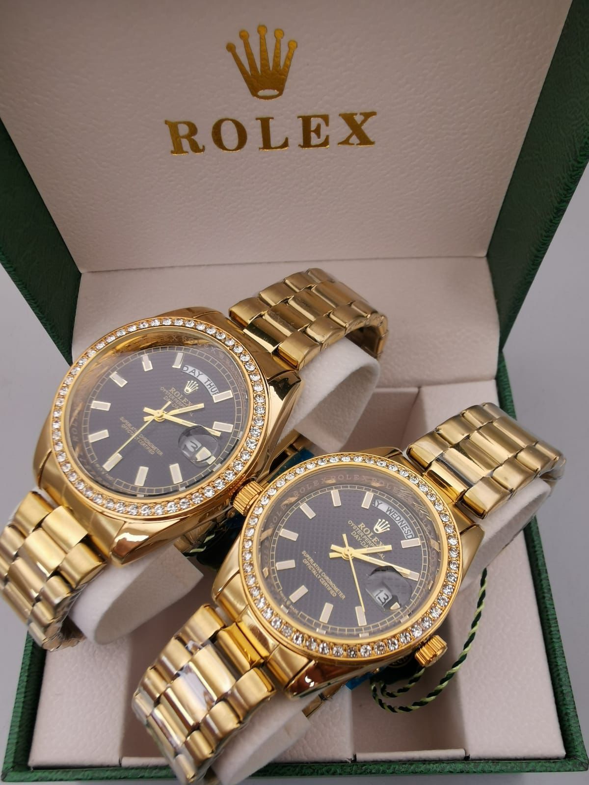 Dos relojes Rolex de oro con biseles de diamantes en una caja verde.