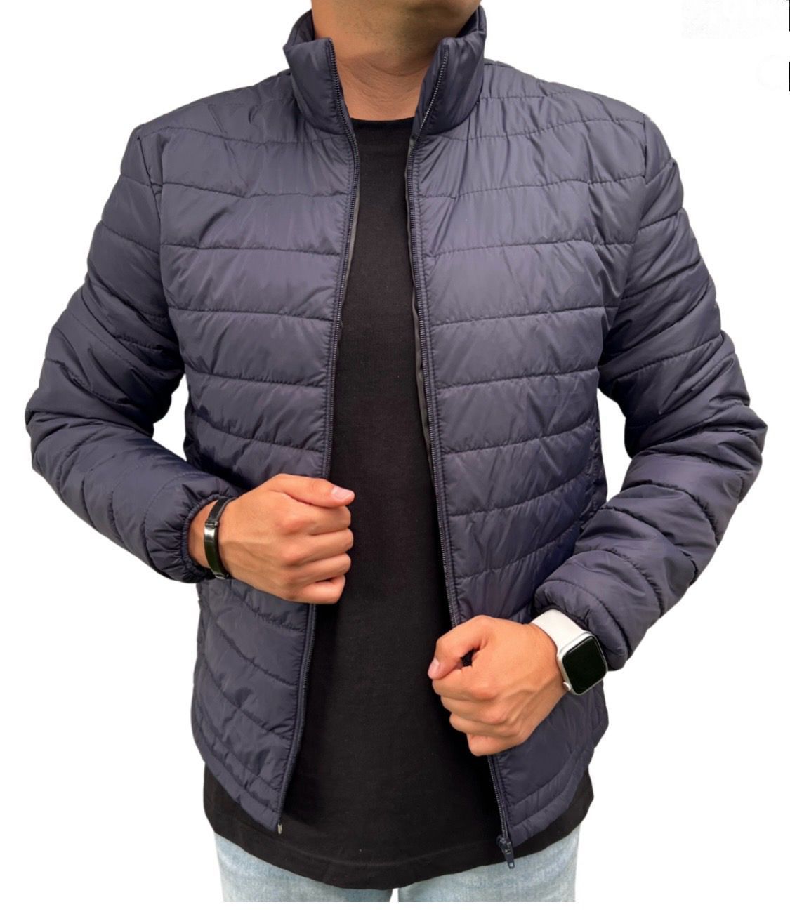 Hombre que lleva una chaqueta acolchada azul marino, de pie sobre un fondo blanco.
