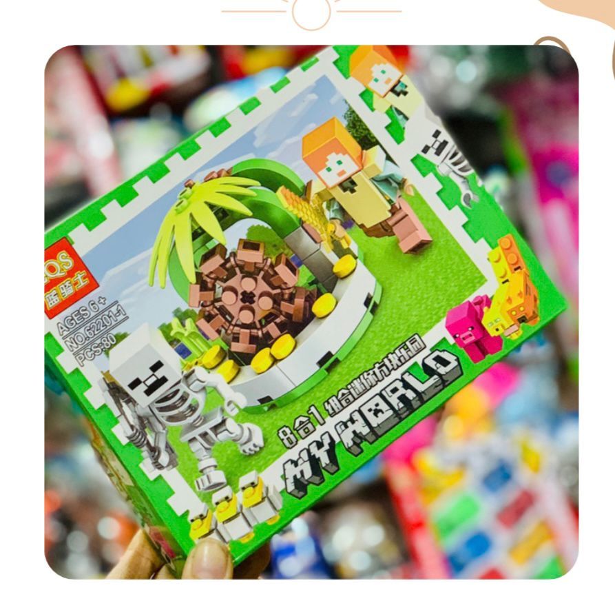 Caja de bloques de construcción con temática de Minecraft con figuras de Alex y un esqueleto, además de un árbol y una isla.