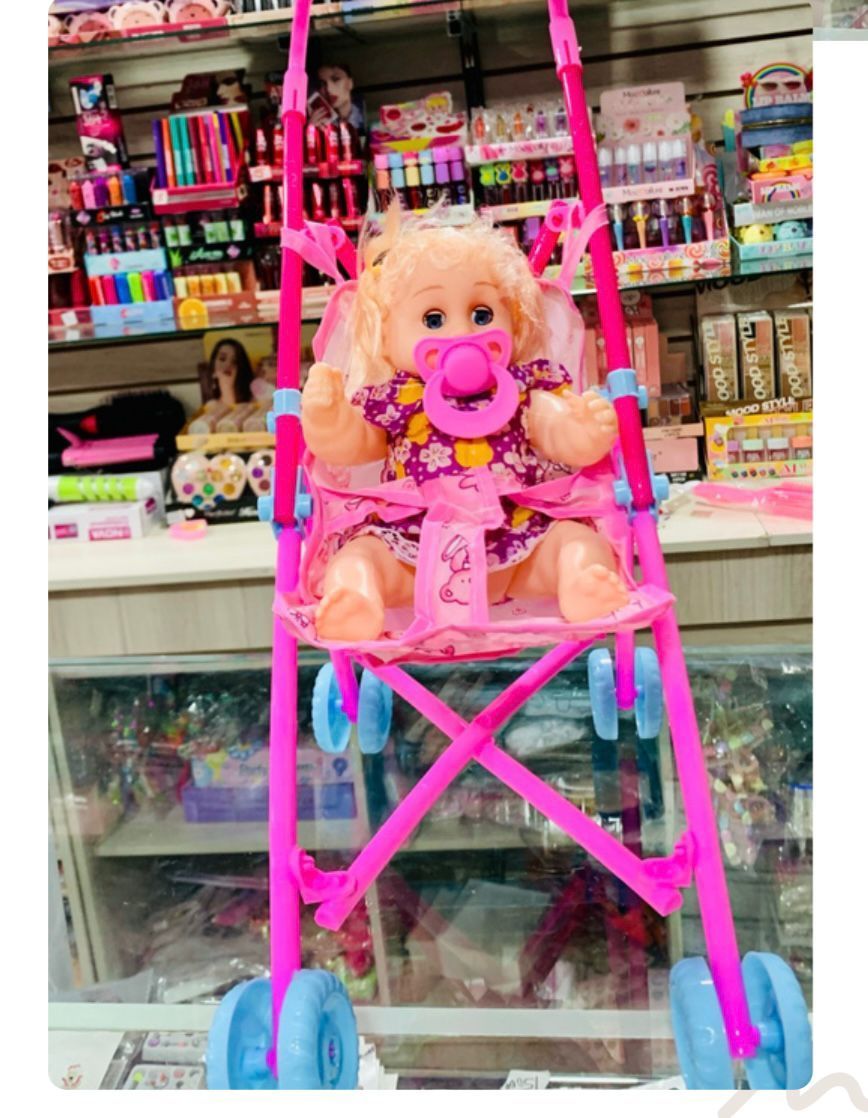Cochecito de juguete rosa con una muñeca dentro de una juguetería.