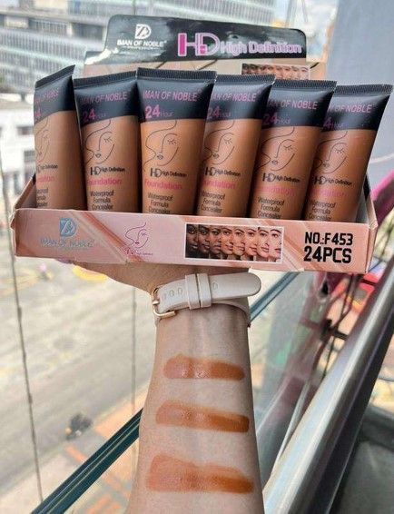 Tubos de maquillaje en caja expositora con brazo que muestra muestras, todas en varios tonos de marrón.