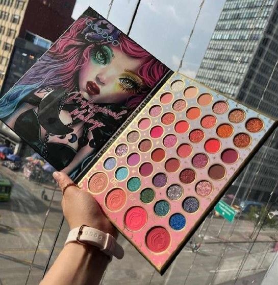 Paleta de sombras de ojos de maquillaje con variedad de colores, sobre un fondo de ciudad.