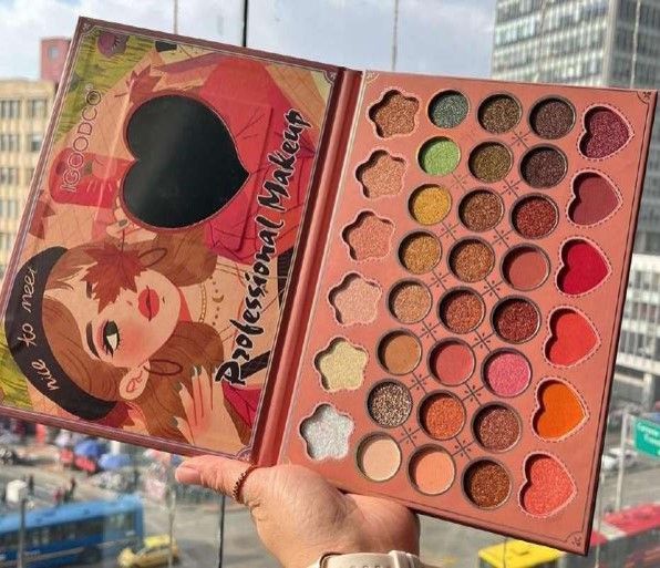 Paleta de maquillaje con varios colores de sombras de ojos; sostenida frente a una ventana.