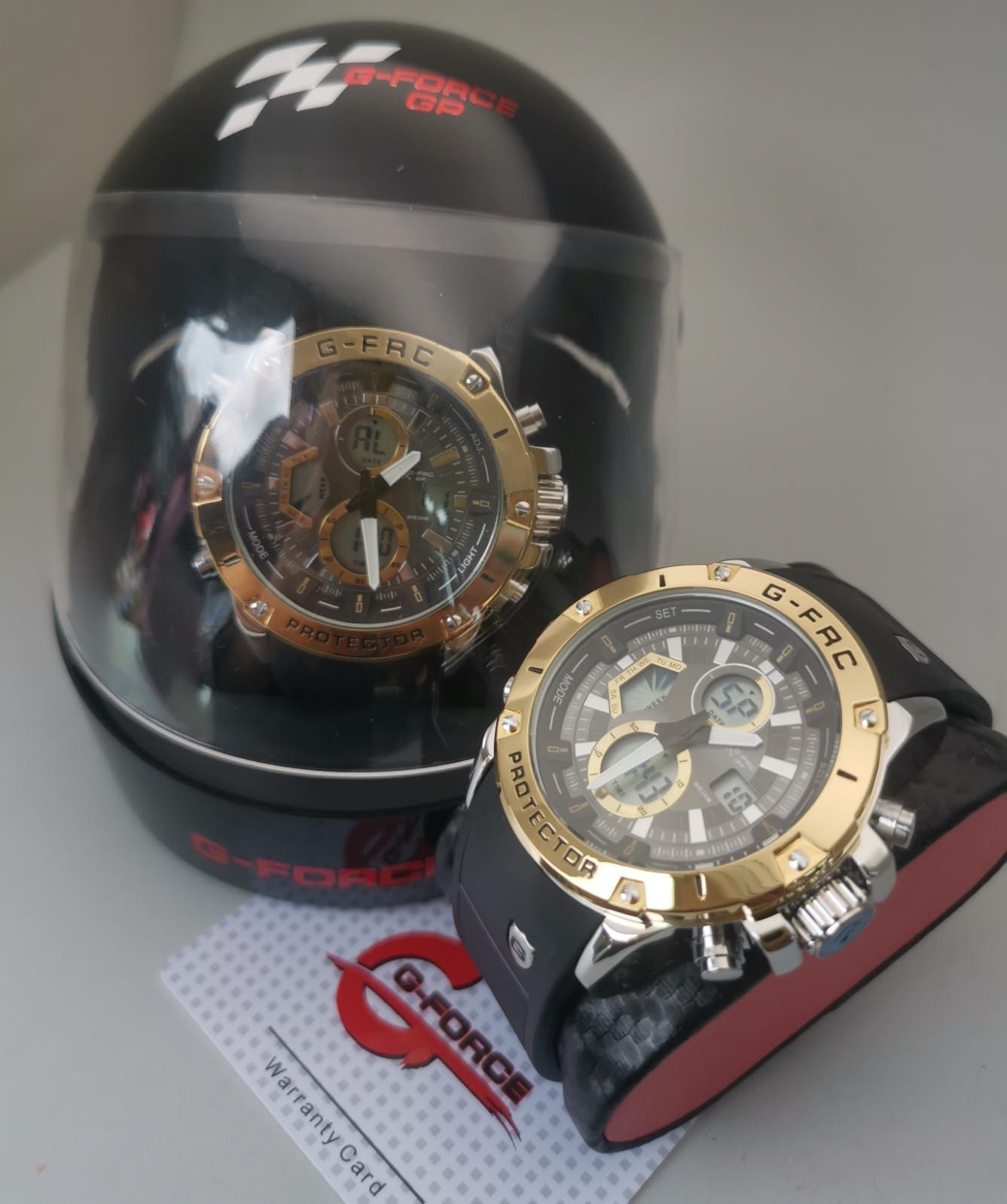 Dos relojes G-Force: uno dentro de una vitrina de casco negra y el otro sobre un soporte.