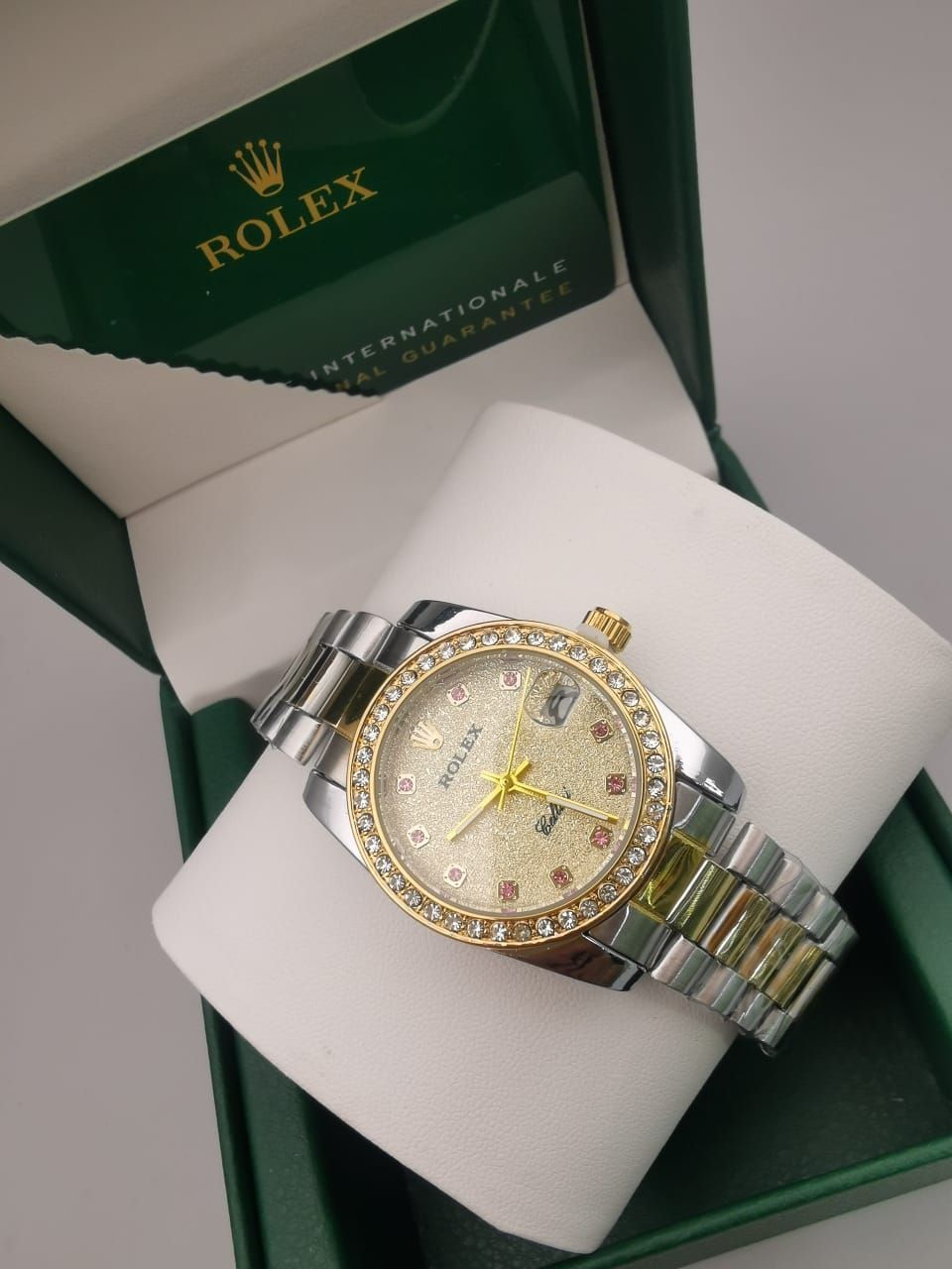 Reloj Rolex en caja con correa bicolor plateada y dorada, bisel y esfera con diamantes.
