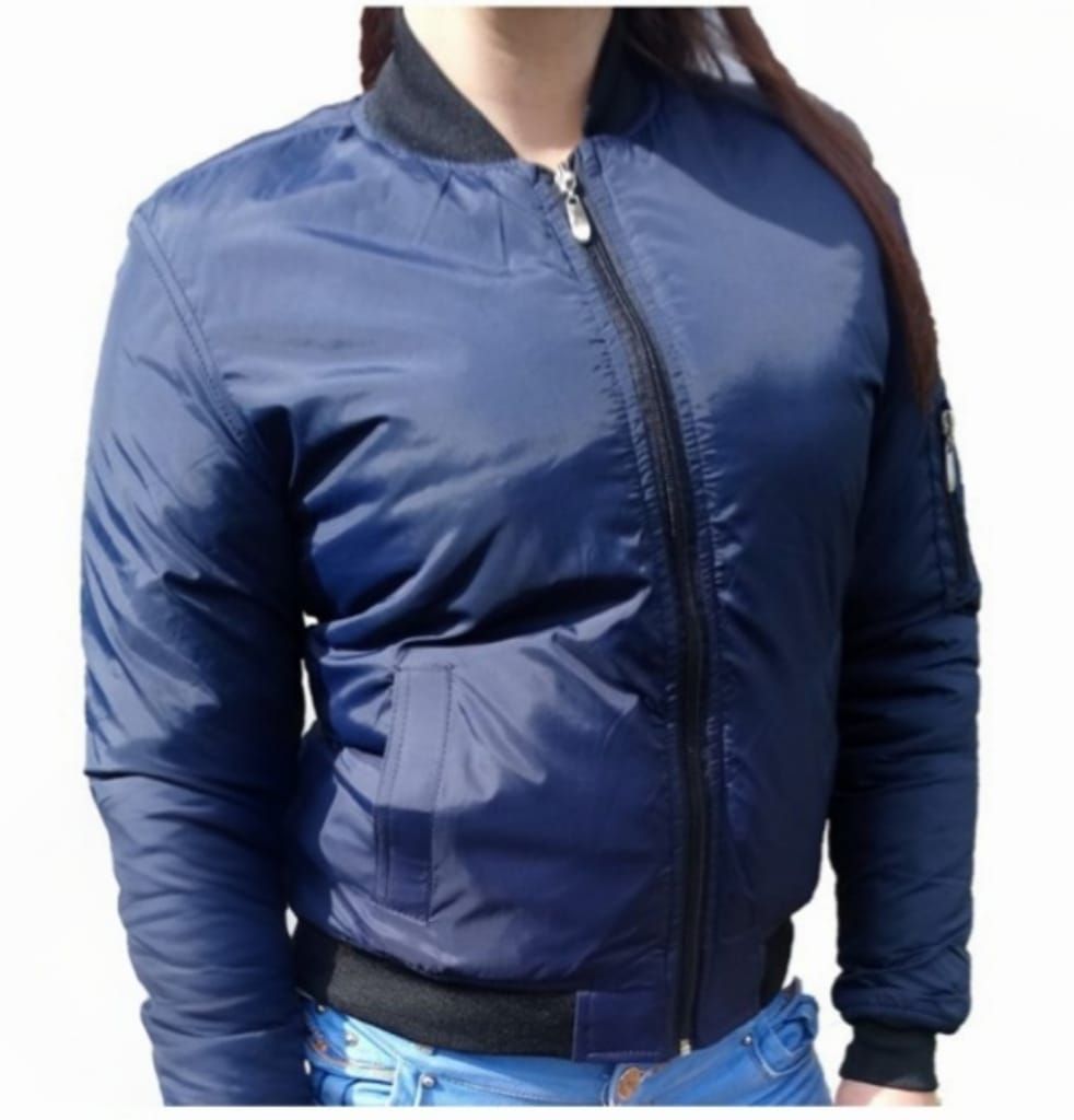 Mujer que lleva una chaqueta bomber color canela con ribete negro y cremallera cerrada.