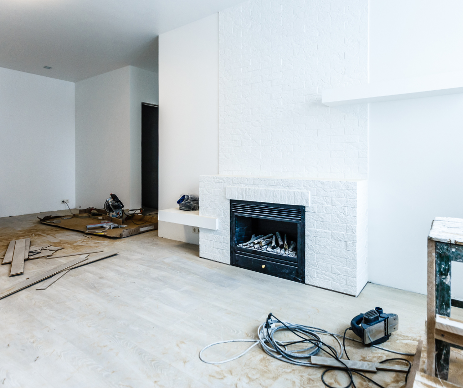 Pièce vide aux murs blancs, avec cheminée et outils, en cours de rénovation.
