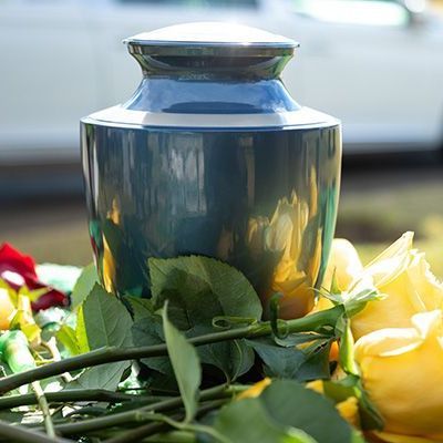 Blue funeral urn surrounded by yellow and red flowers