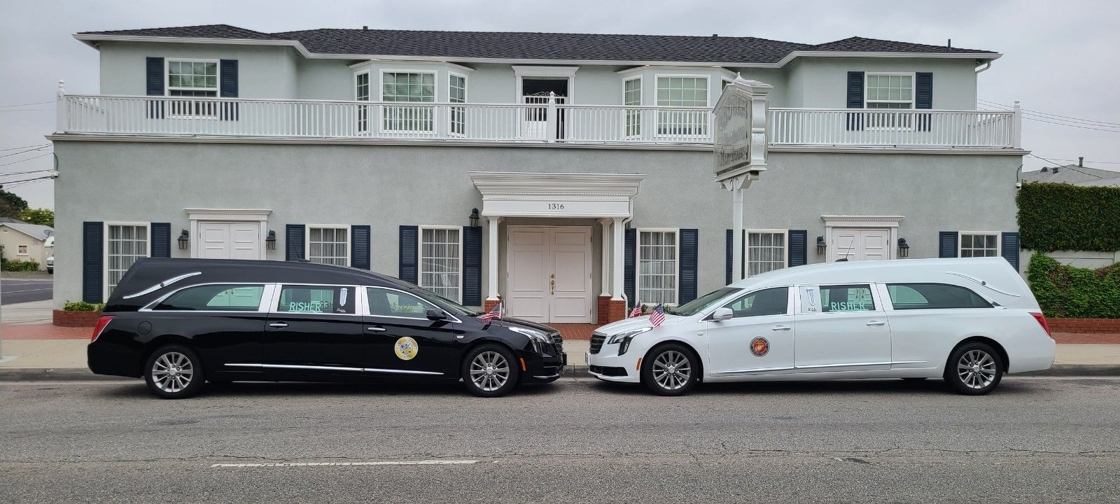 Black sedan and white minivan parked in front of a light gray two-story house with a front entrance