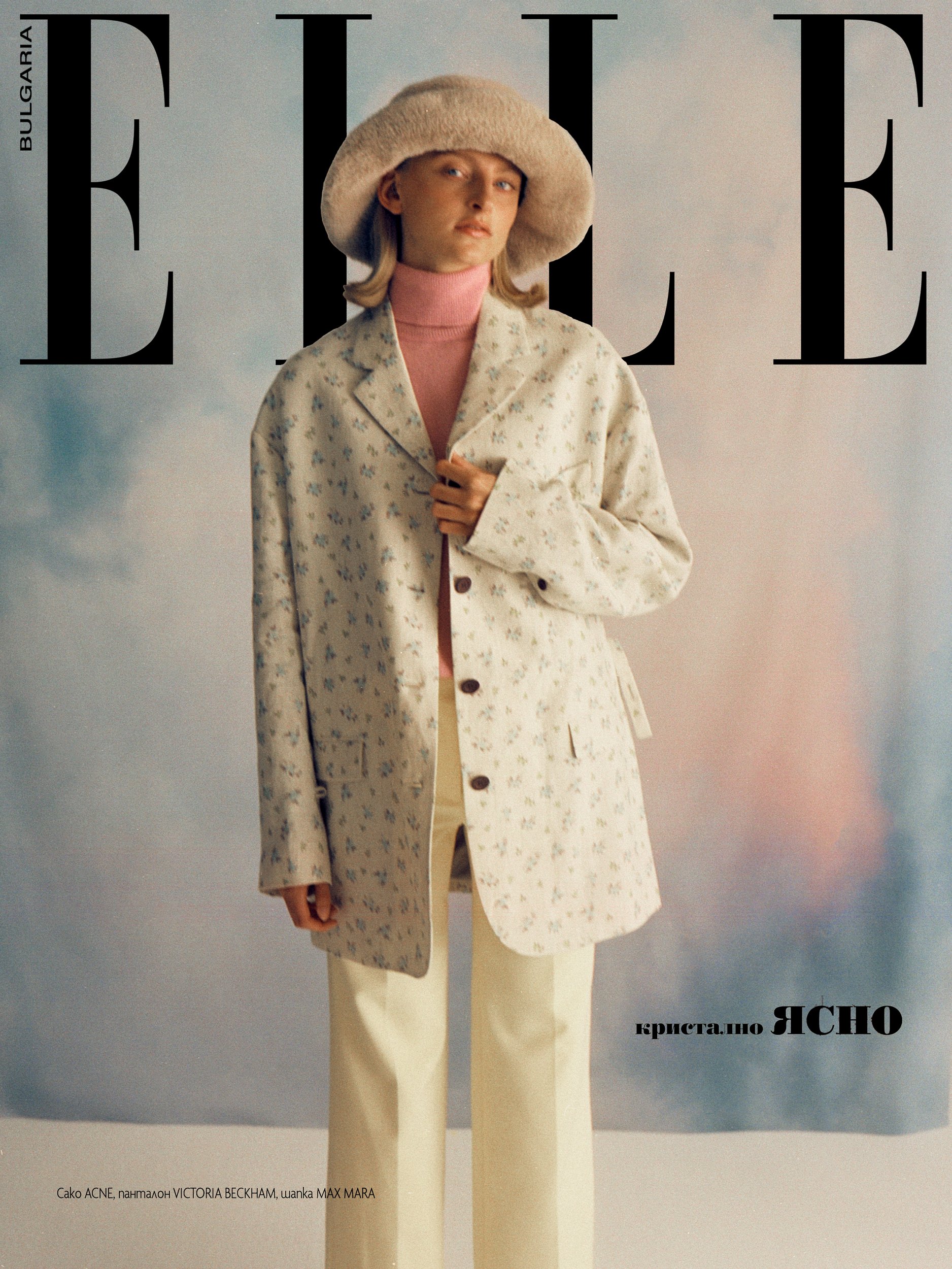 Cover des ELLE-Magazins: Frau in geblümter Jacke, rosa Rollkragenpullover und Hut, stehend.