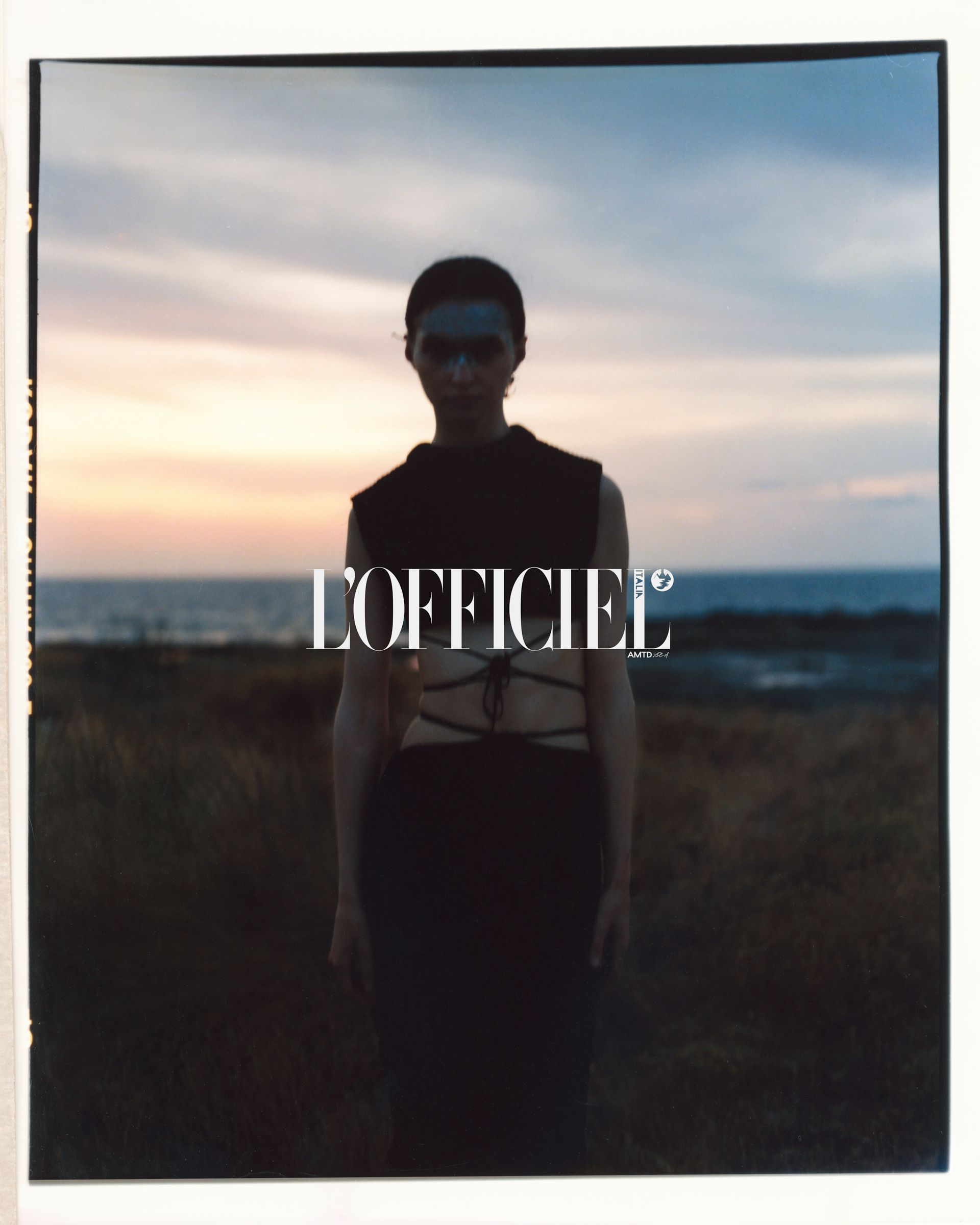 Model in schwarzem Outfit vor Sonnenuntergang im Hintergrund, L'OFFICIEL-Logo.