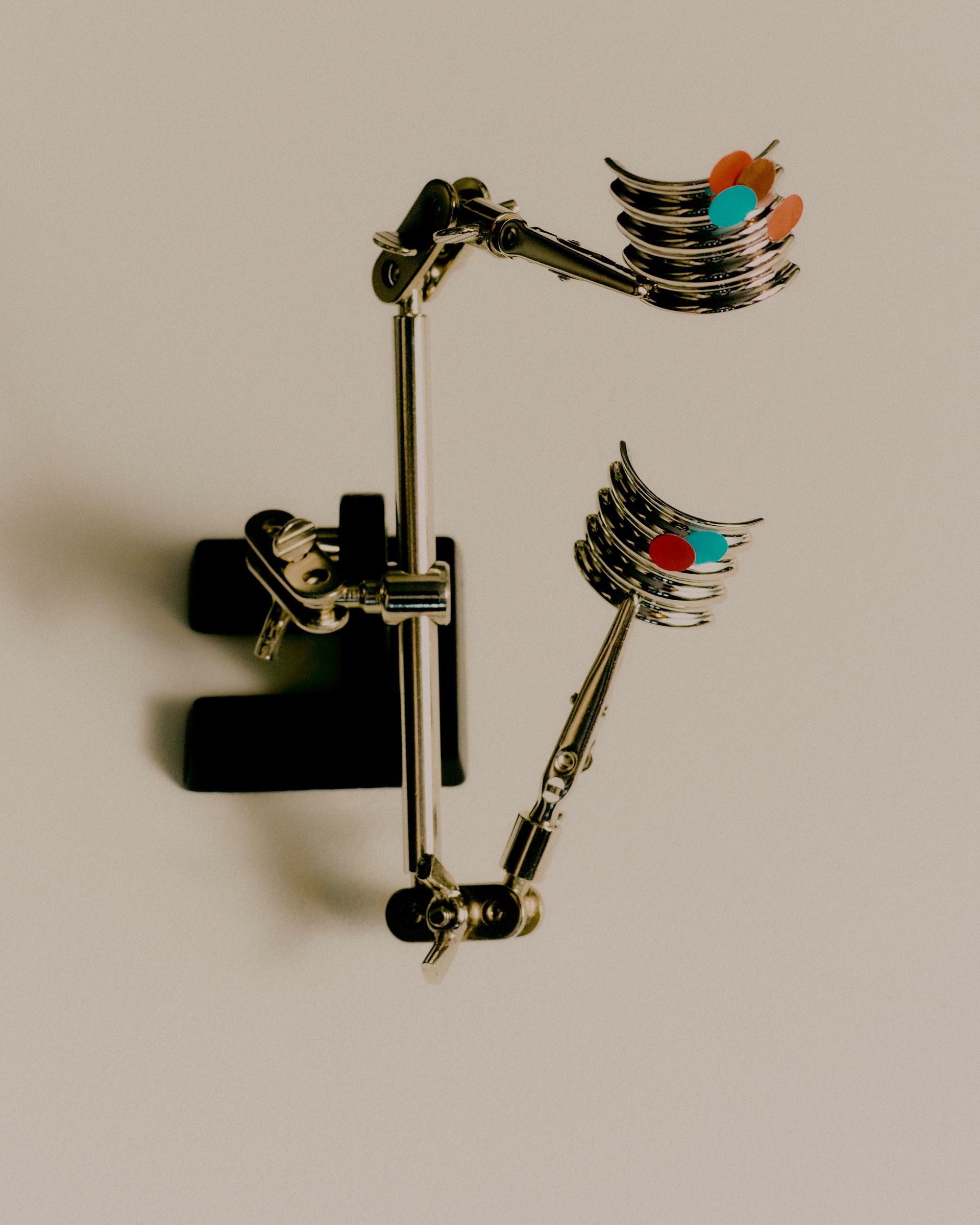 Kieferorthopädisches Gerät mit Metallarmen, das zwei Sätze künstlicher Zähne mit roten und blauen Punkten hält.