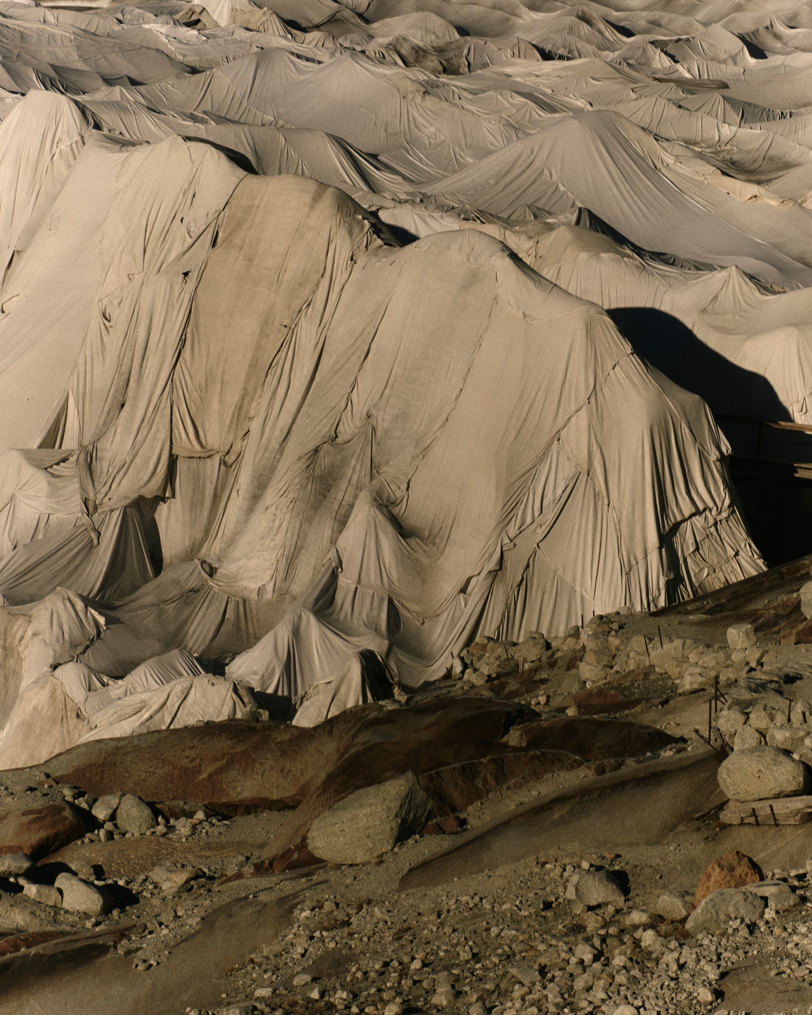 Graues, zerklüftetes Berggelände mit vielen Bergrücken und Fußspuren im Schnee.