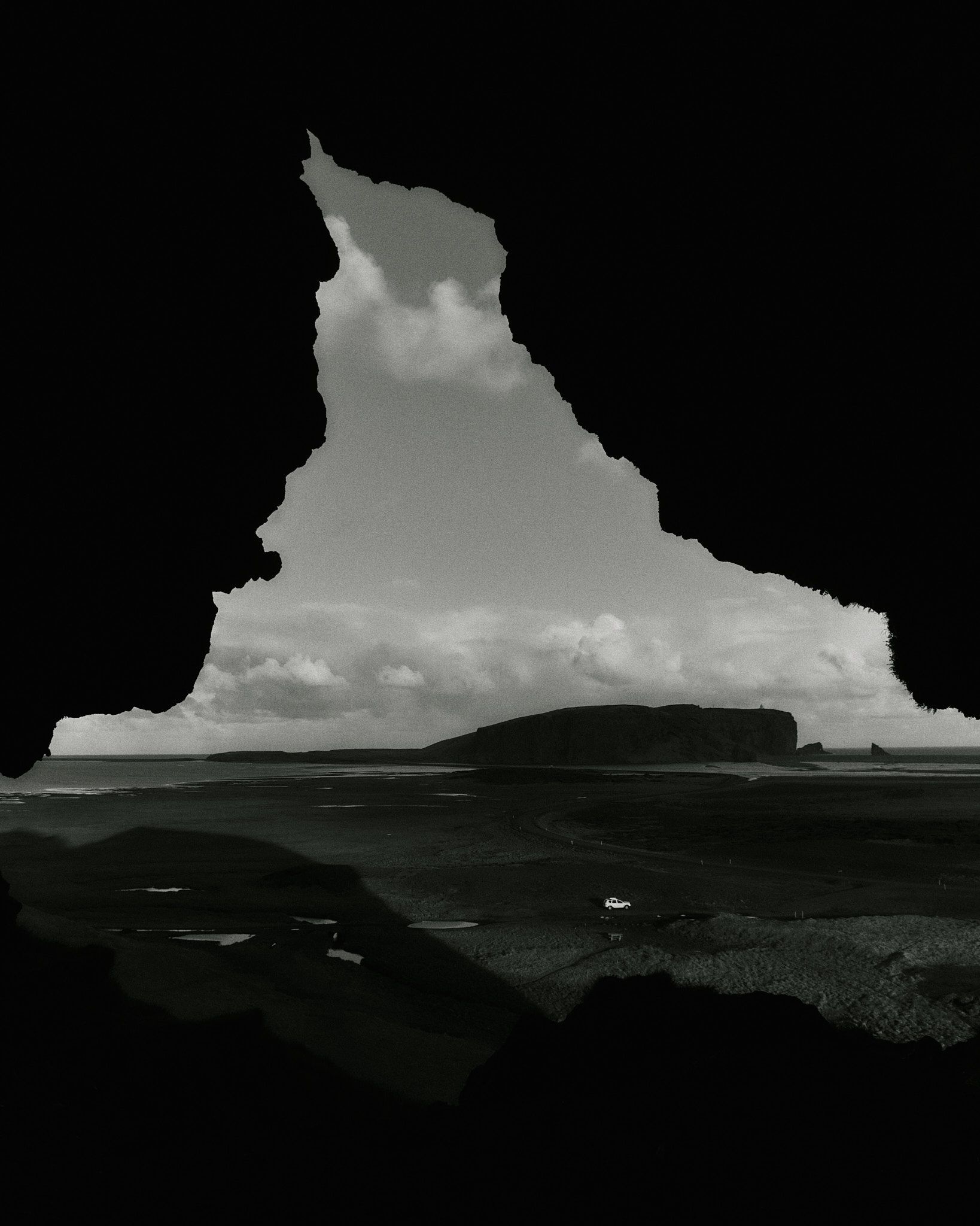 Schwarzweißfoto einer Küstenlandschaft, eingerahmt von einer dunklen, unregelmäßigen Form.