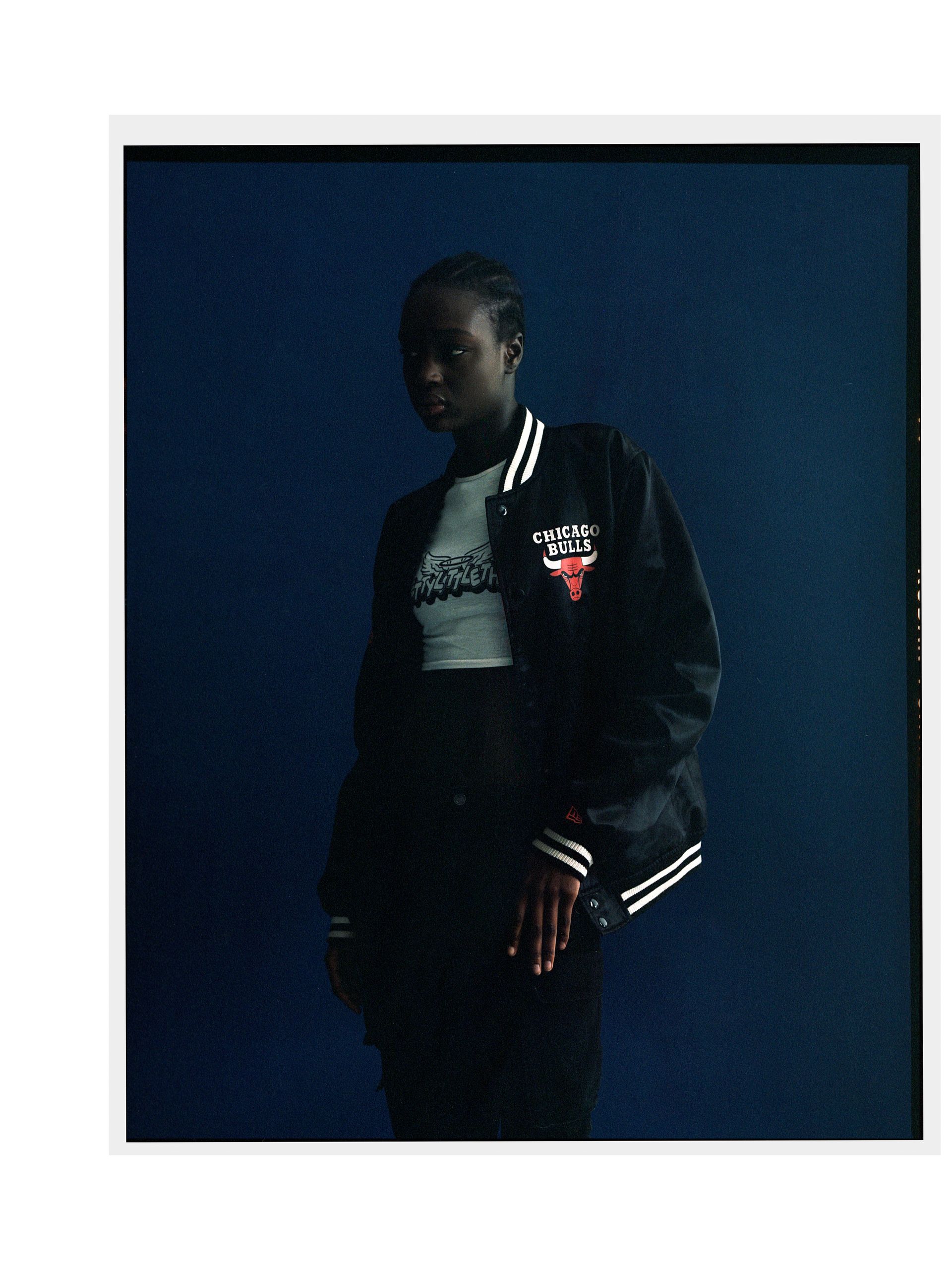 Person mit einer schwarzen Jacke der Chicago Bulls, die vor einem dunkelblauen Hintergrund steht.