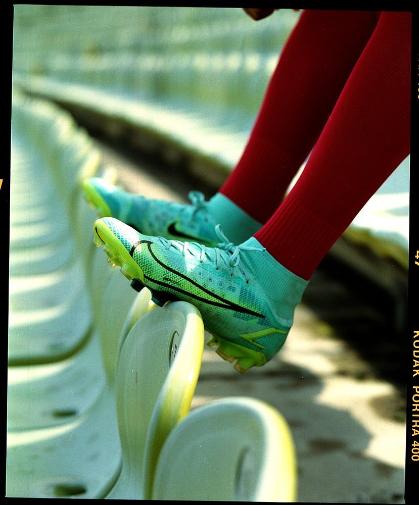 Fußballschuhe auf Stadionsitzen, mit roten Socken.