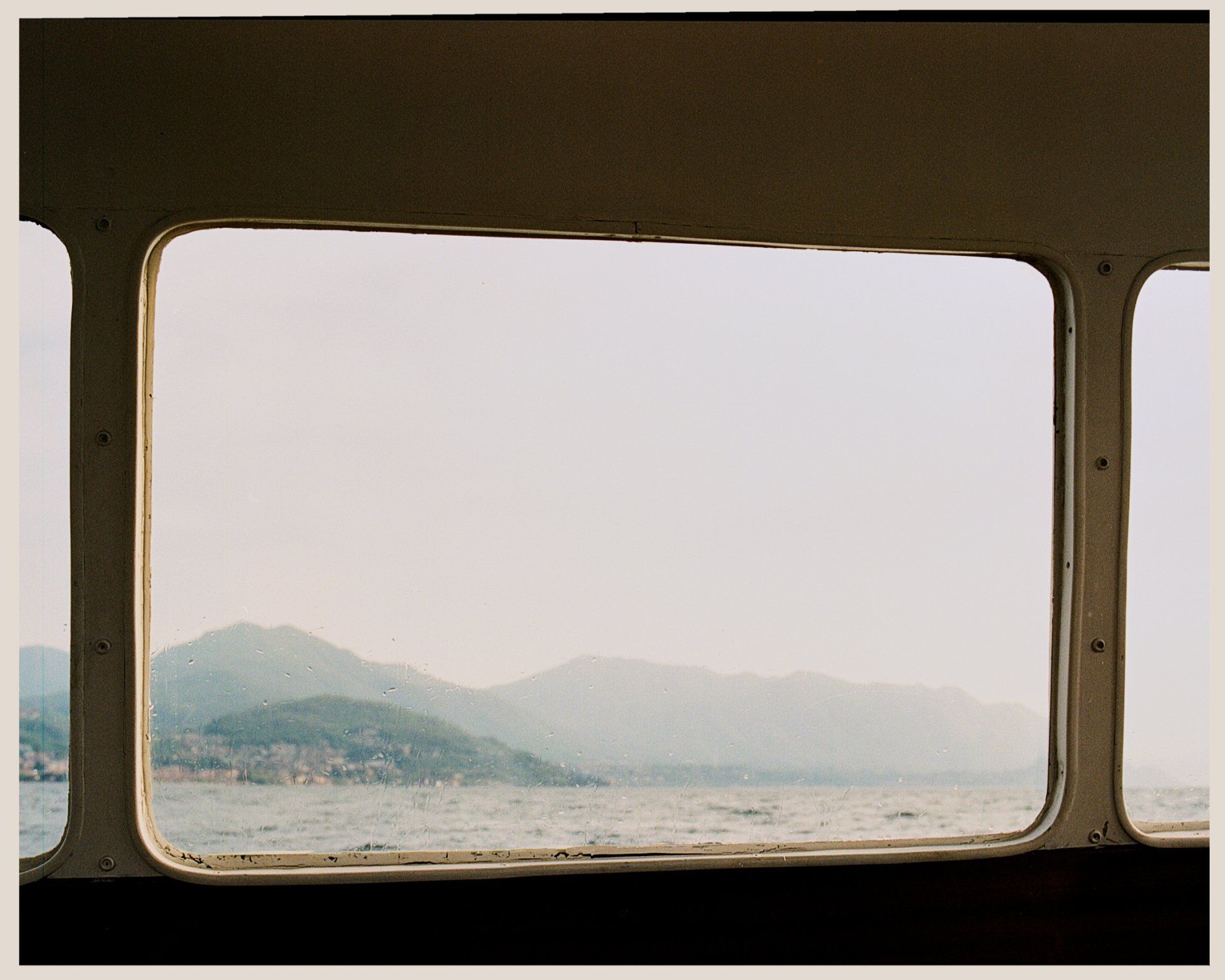 Blick auf Berge und Wasser durch ein Fenster. Sanftes Licht und dunstige Atmosphäre.