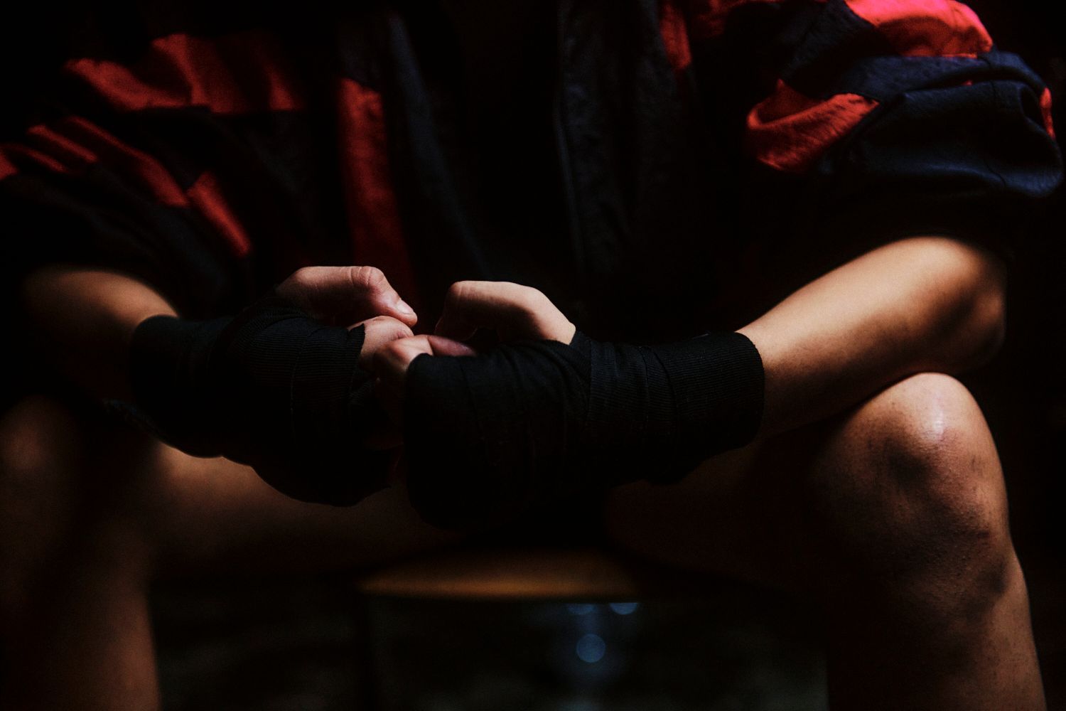 Eine Person wickelt schwarze Handbandagen und bereitet sich auf einen Boxkampf vor.