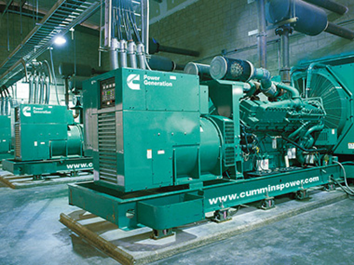 Green Cummins power generators in a utility room.