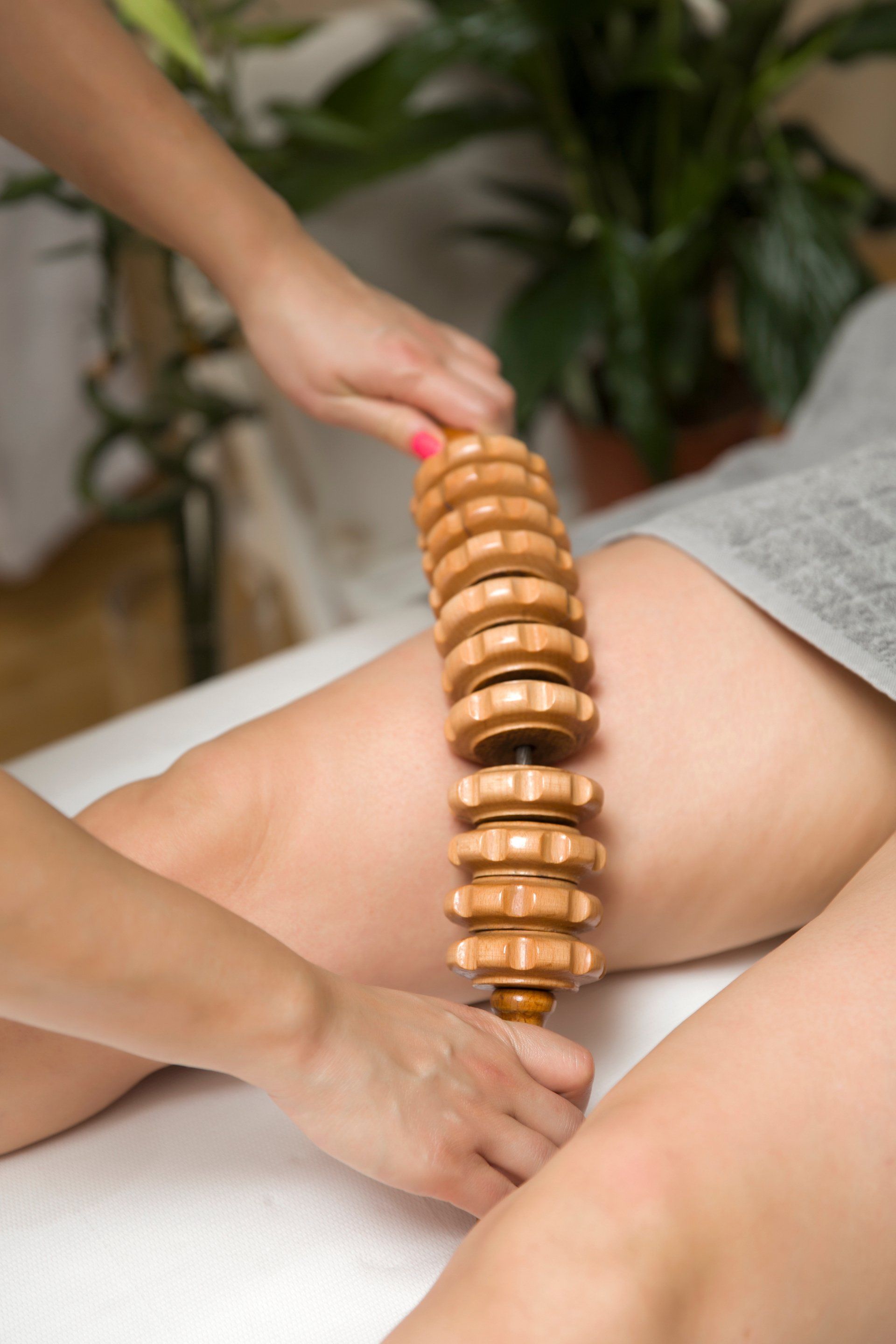 Eine Frau bekommt eine Beinmassage mit einem Holzstab.
