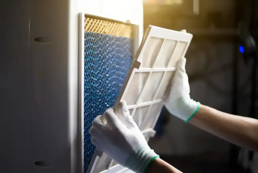 Person wearing gloves replacing air filter in an air purifier.