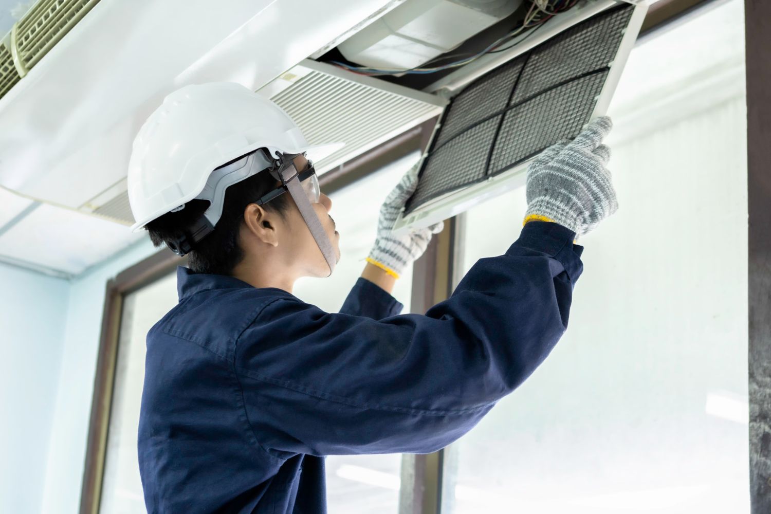Person in uniform replacing air filter in an air vent.