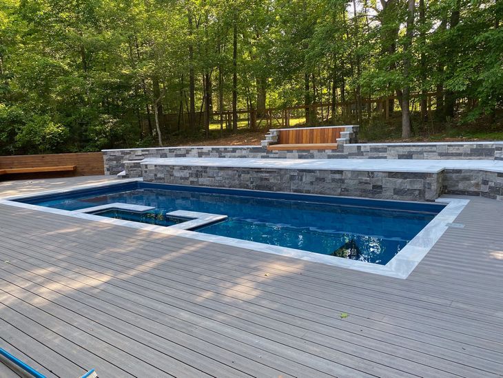 a large swimming pool surrounded by trees and a wooden deck