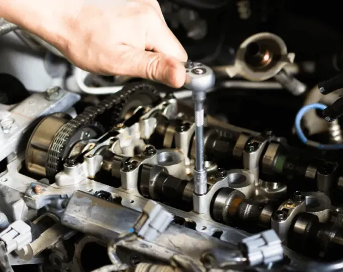 Mechanic in gloves inspecting a car engine bay.
