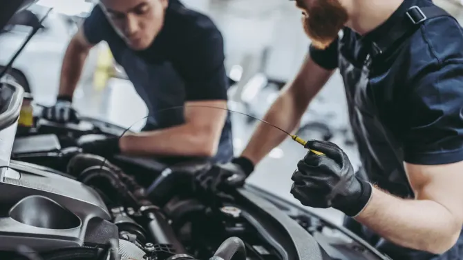 Mechanic checking car oil level with a dipstick.