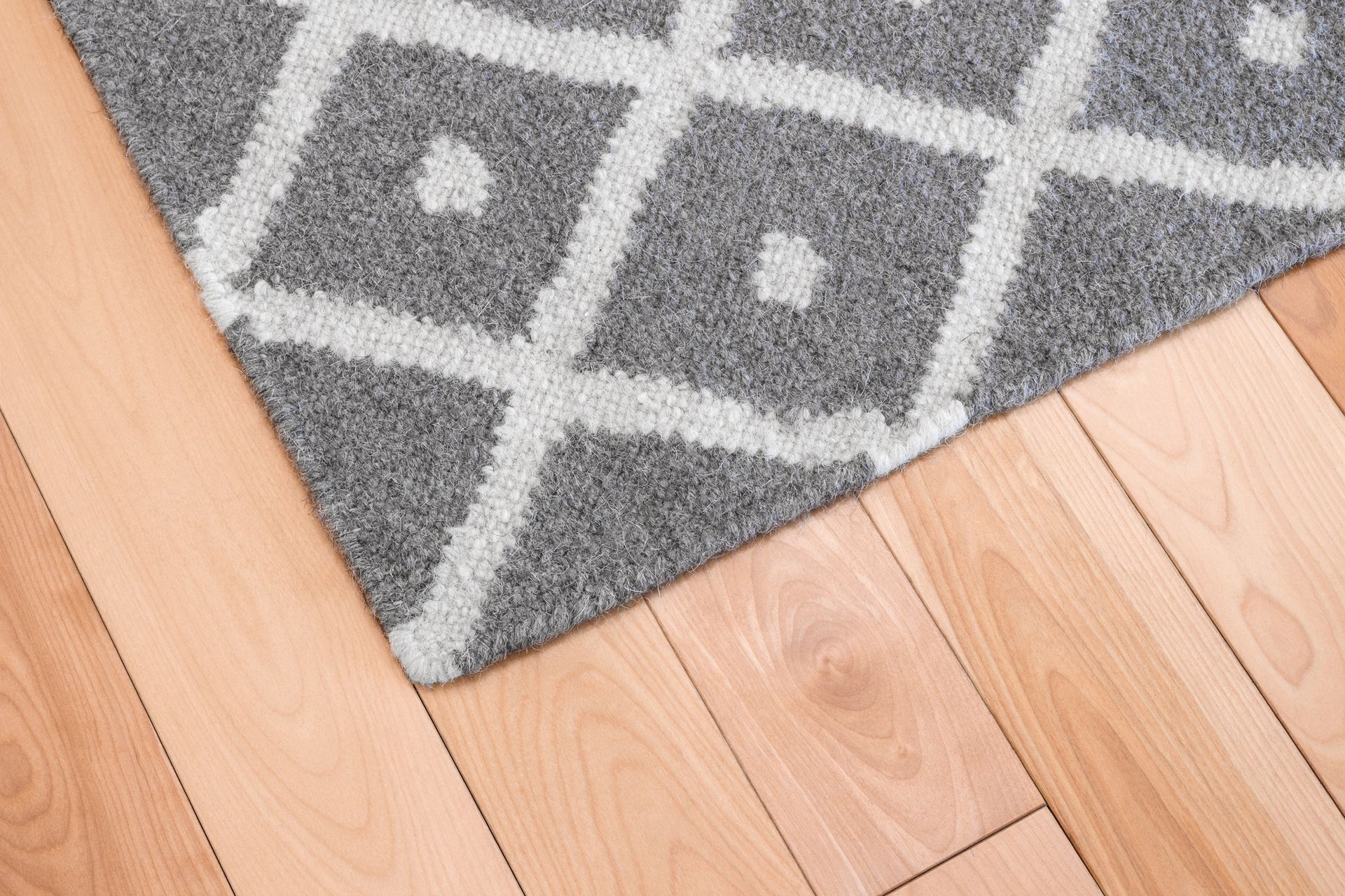 A gray and white rug is on a wooden floor.