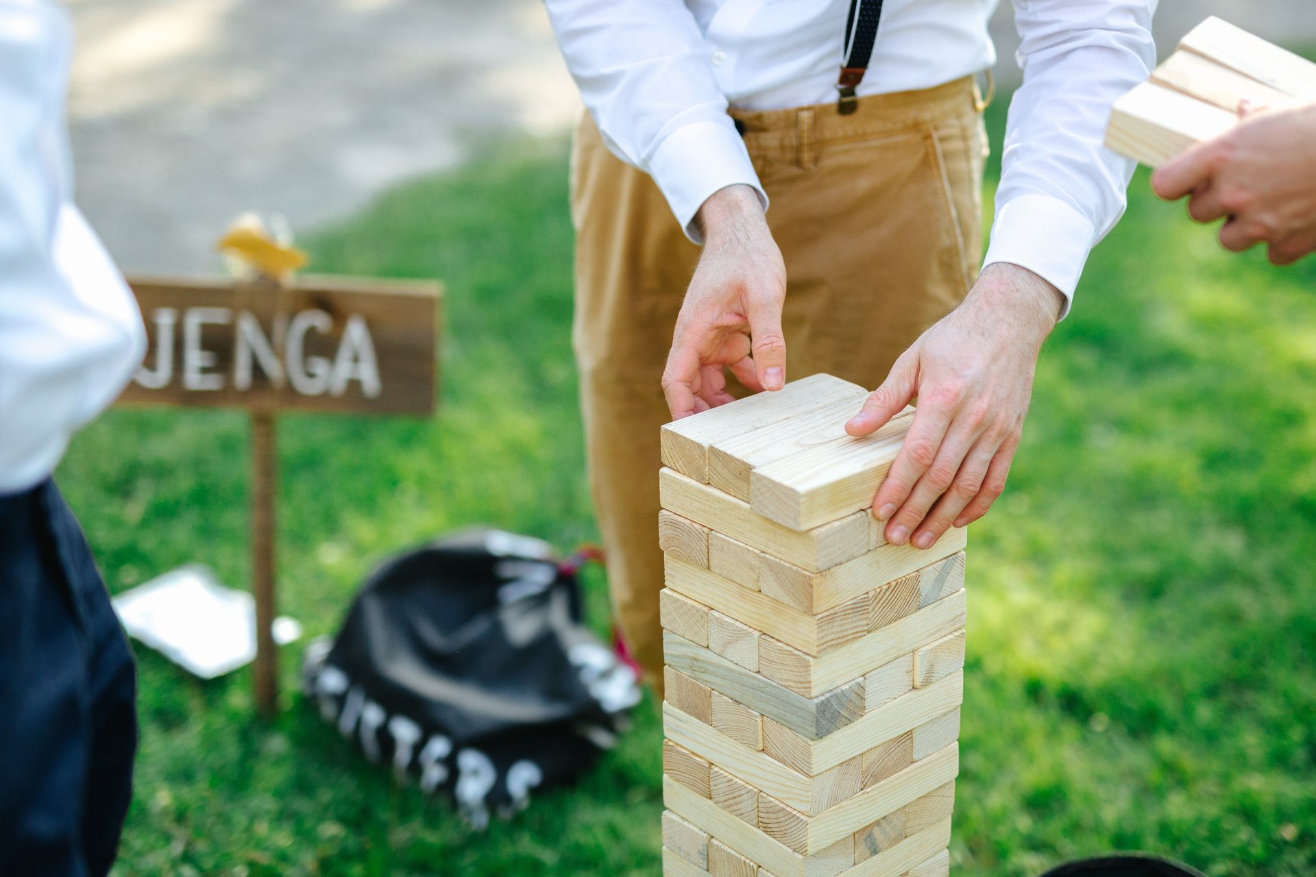 People playing Jenga outdoors; one removing a block from the tower.