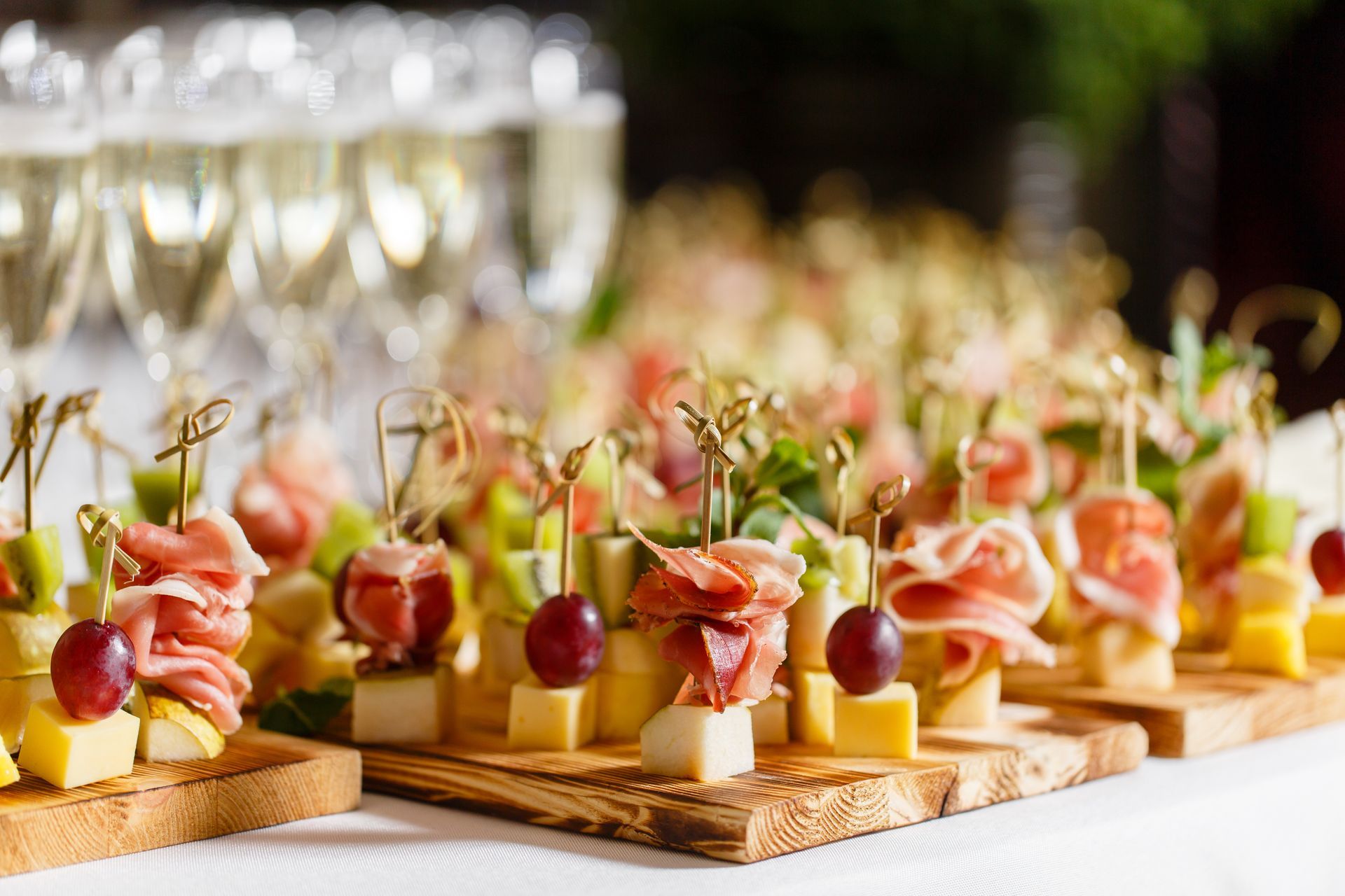 Appetizer skewers on wooden boards beside champagne glasses for barn wedding catering.