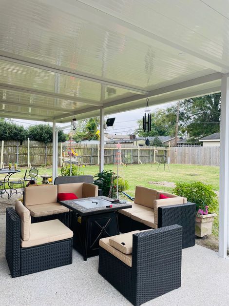 Wooden deck with red pergola overlooking a lush green lawn and trees under a partly cloudy sky