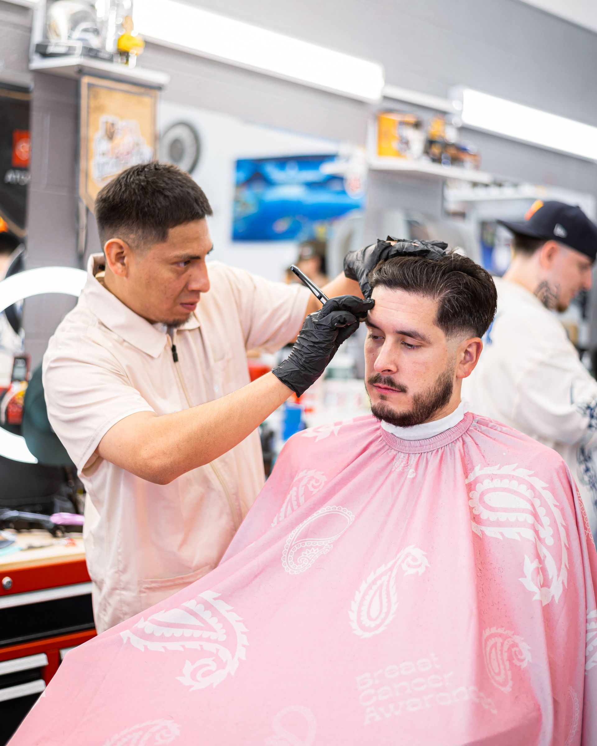 Barber trimming a client’s hair with clippers in a bright barbershop