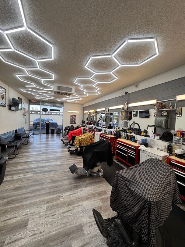 Bright salon interior with hexagon ceiling lights, styling chairs, mirrors, and red tool carts along the wall