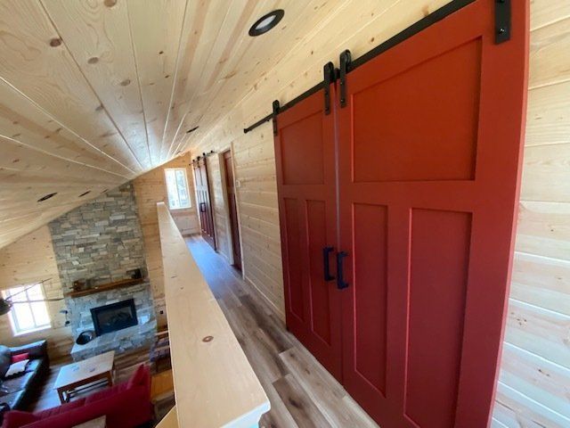 Red barn doors on track above a living room. Wooden walls and ceiling.