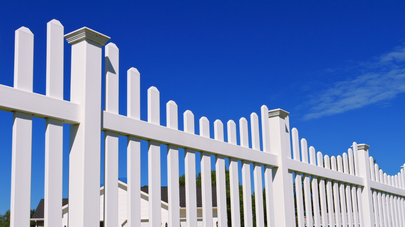 White picket fence against a bright blue sky.