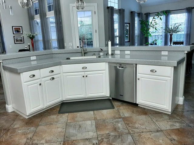 White kitchen cabinets with a gray countertop and stainless steel dishwasher.